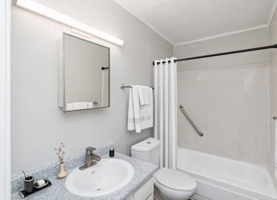 Model Bathroom with White Cabinets, Wood-Style Flooring and Shower/Tub at Indigo Park Apartments located in Albuquerque, NM.