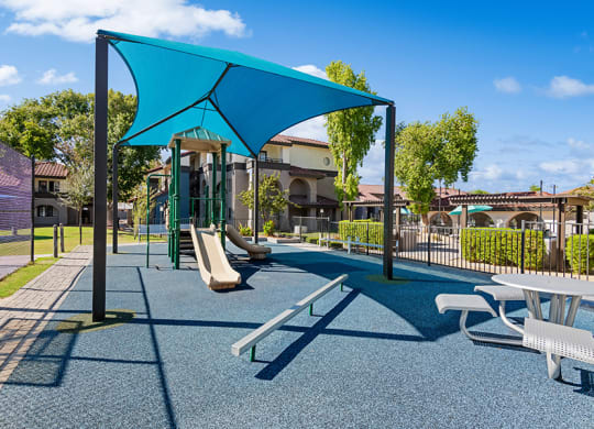 Community Playground with Slide and Blue Canopy at Stillwater Apartments in Glendale, AZ.