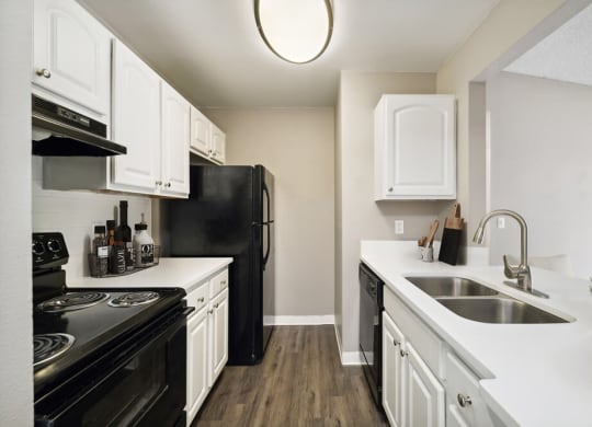 Model kitchen with white cabinets and black appliances at Vue at Baymeadows Apartments in Jacksonville, Florida
