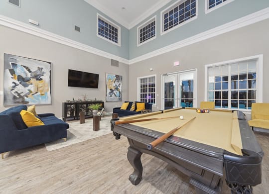 Community Clubhouse with Lounge Furniture and Pool Table Area at Vinings at Hunter's Green Apartments in Tampa, FL.