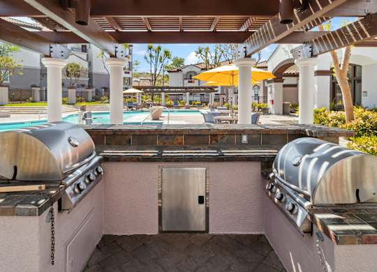 A BBQ grill is on a patio next to a pool.