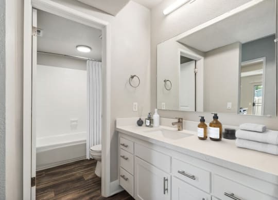 Model Bathroom 2 with Bathtub/Shower, Wood-Style Flooring & White Cabinets at Forest Park Apartments in El Cajon, CA.