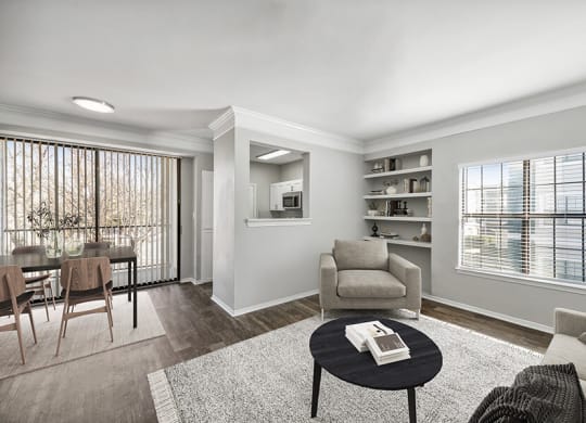 Model Living Room and Dining Room with Wood-Style Flooring and Patio Accessibility at Bridges at Oakbend Apartments located in Lewisville, TX.