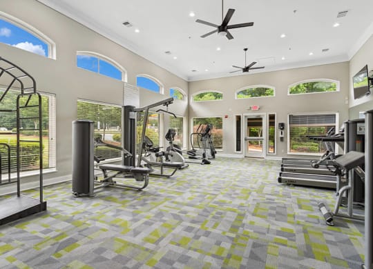 a spacious fitness center with exercise equipment and windows