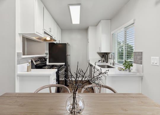 Model Kitchen with White Cabinets and Wood-Style Flooring at Colonnade at Fletcher Hills Apartments in El Cajon, CA.