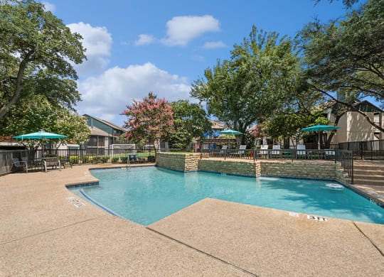 Community Swimming Pool with Pool Furniture at Bridges at Deer Run Apartments in Dallas, TX.