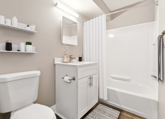 Model Bathroom with White Cabinets, Wood-Style Flooring and Shower/Tub at Heights at Marlborough Apartments located in Marlborough, MA.