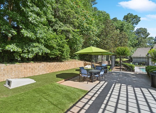 Outdoor Picnic Area with Lounge Furniture and Corn Hole Sets at Retreat at Stonecrest Apartments located in Lithonia, GA.