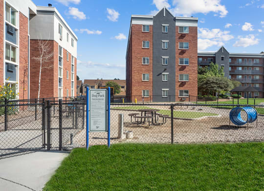 a fenced in park with a playground and apartment buildingsat Esprit Cherry Creek, Glendale, CO