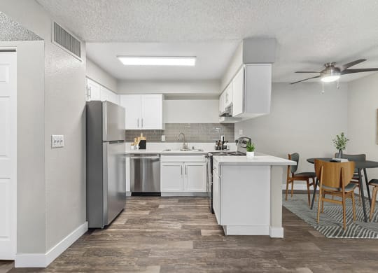 Model Kitchen with White Cabinets and Wood-Style Flooring with view of Dining Room at Meadow Ridge Apartments in Las Vegas, NV.