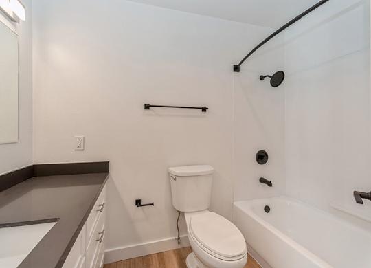 Model Bathroom with White Cabinets and Wood-Style Flooring at Palmilla Apartments located in San Diego, CA.