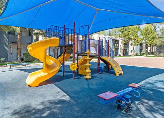 Community Playground with a Slide and Blue Canopy at Solano Springs Apartments in Tucson, AZ.