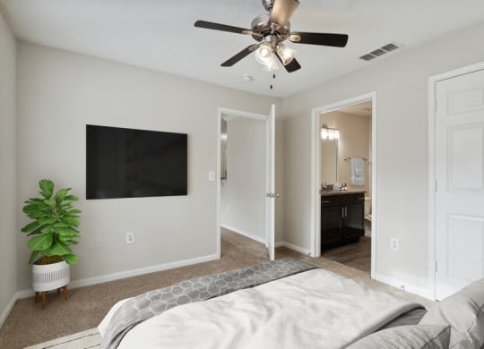 Model bedroom with ceiling fan and attached bath