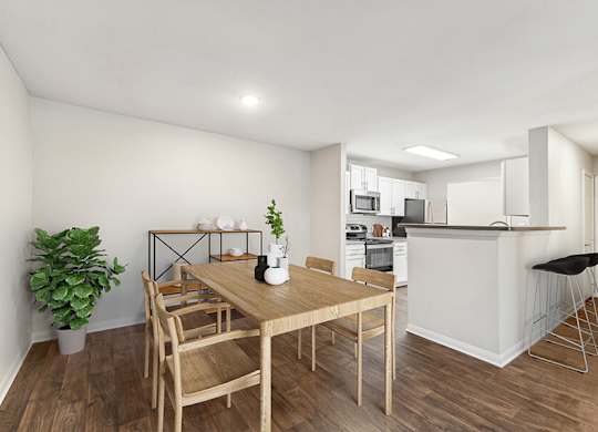 Model Dining Room with Wood-Style Flooring and View of Kitchen at Lake Cameron Apartments located in Apex, NC.