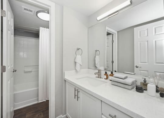 Model Bathroom with White Cabinets, Wood-Style Flooring and Shower/Tub at Crystal Creek Apartments located in Phoenix, AZ.