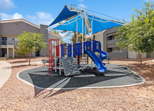 Community Playground with a Slide and Blue Canopy at Verraso Apartments in Las Vegas, NV.