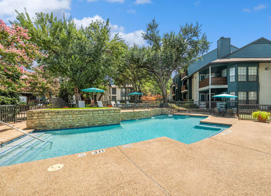 Community Swimming Pool with Pool Furniture at Bridges at Deer Run Apartments in Dallas, TX.
