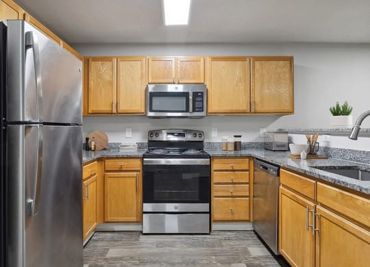 Model Kitchen with Wood-Style Flooring and Oak Cabinets at Retreat at Stonecrest Apartments located in Lithonia, GA.
