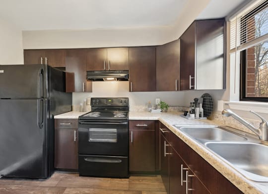 Model Kitchen with Brown Cabinets and Tile Flooring at Spring Forest Apartments in Raleigh, NC.