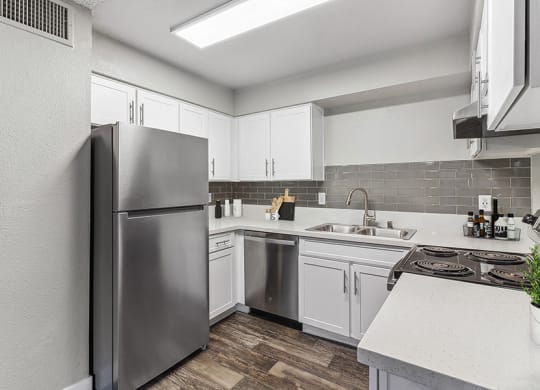 Model Kitchen with White Cabinets and Wood-Style Flooring at Meadow Ridge Apartments in Las Vegas, NV.