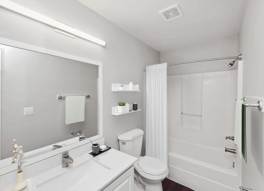Model Bathroom with White Cabinets, Wood-Style Flooring and Shower/Tub at Vue at Baymeadows Apartments in Jacksonville, FL.