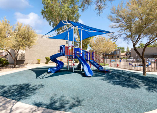 a playground with a blue and red slide at the villas at falling waters townhomes at Villages at Metro Center, Phoenix, Arizona