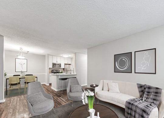 Model Living Room with Wood-Style Flooring and View of Kitchen/Dining Area at Commons at Haynes Farm Apartments in Shrewsbury, MA.