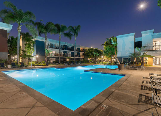 Community Swimming Pool with Pool Furniture at Madison Park Apartments located in Anaheim, CA.