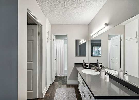 Model Bathroom with White Cabinets and Wood-Style Flooring at Madison Park Apartments located in Anaheim, CA.