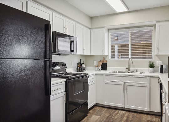 Model Kitchen with White Cabinets and Wood-Style Flooring at Verraso Apartments in Las Vegas, NV.