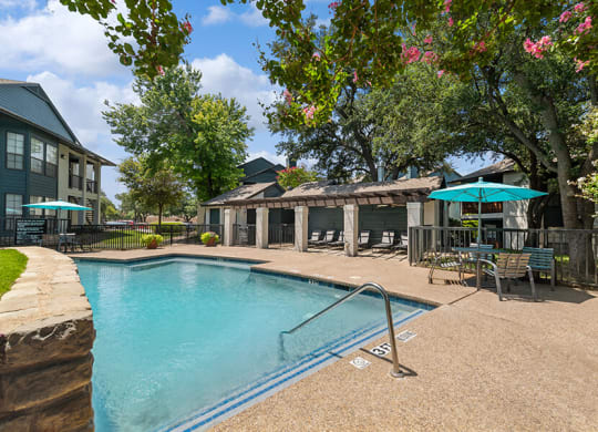 Community Swimming Pool with Pool Furniture at Bridges at Deer Run Apartments in Dallas, TX.