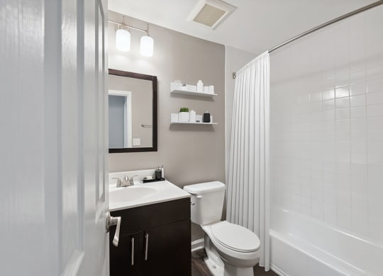 Model Bathroom with Dark Cabinets, Wood-Style Flooring and Shower/Tub at Spring Forest Apartments in Raleigh, NC.