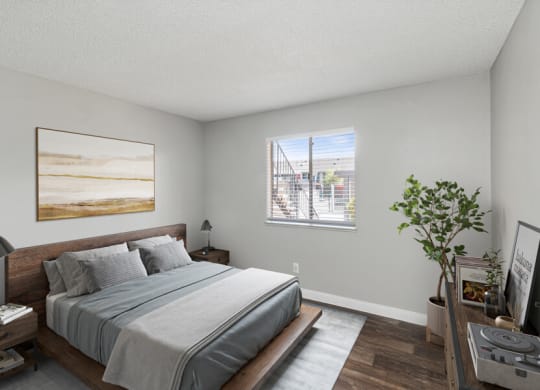 West Las Vegas, NV Apartments - Accent on Rainbow - Primary Bedroom With Wood Frame Bed, Gray Bedding, Matching Nightstands, Wall Art, And Window Blinds