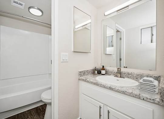 Model Bathroom with White Cabinets, Wood-Style Flooring and a Shower/Tub at Butler Ridge Apartments located in Glendale, AZ.