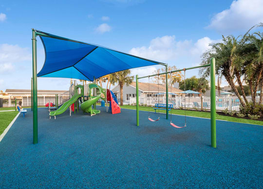 Community Playground with Slide, Swing Set and Blue Canopy at Park at 7200 Apartments in Jacksonville, FL.
