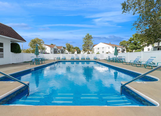 Community Swimming Pool with Pool Furniture at Village at Marshfield Apartments located in Marshfield, MA.