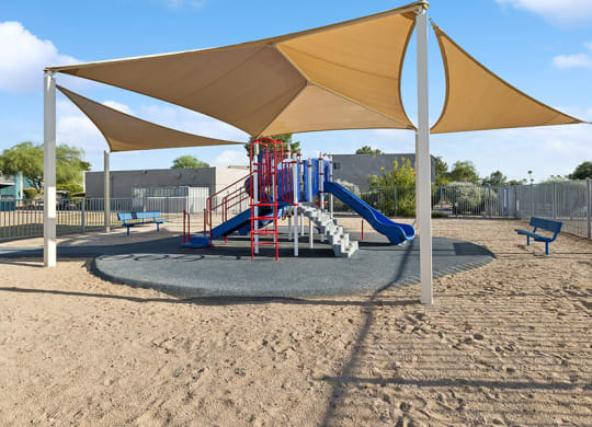Community Playground with Slide and Tan Canopy at Tanque Verde Apartments located in Tucson, AZ.