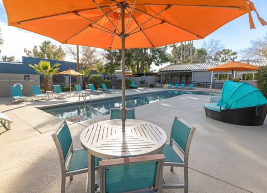 A table with an umbrella and chairs next to a pool  at Lakeside Casitas in Tucson, AZ