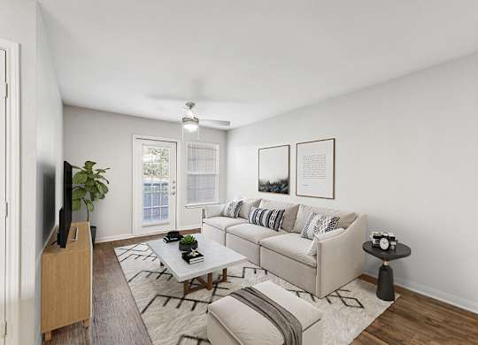 Model Living Room with Wood-Style Flooring and Patio Accessibility at Lake Cameron Apartments located in Apex, NC.