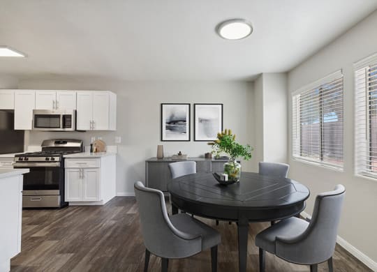 Model Dining Room with Wood-Style Flooring and View of Kitchen at Loma Vista Apartments in Las Vegas, NV.