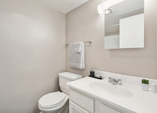 Model Bathroom with White Cabinets and Wood-Style Flooring at Spring Parc Apartments in Silver Spring, MD.