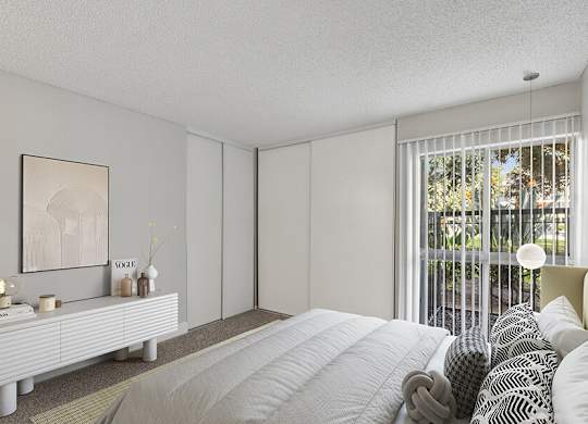 Model Bedroom with Carpet and Patio Accessibility at Madison Park Apartments located in Anaheim, CA.