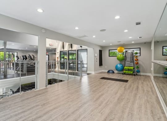 Community Fitness Center with Yoga Area and Wall Mirrors at Dunwoody Village Apartments in Atlanta, GA.