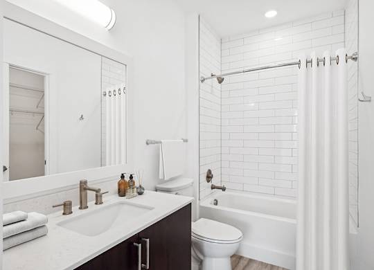 Model Bathroom with Dark Cabinets, Wood-Style Flooring and Shower/Tub at Stella Apartments located in New Carrollton, MD.