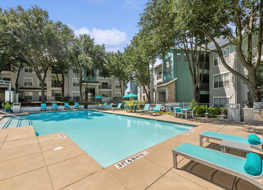 Community Swimming Pool with Pool Furniture at Essence Apartments in Dallas, TX.