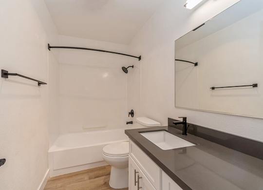Model Bathroom with White Cabinets and Wood-Style Flooring at Palmilla Apartments located in San Diego, CA.
