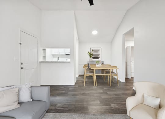 Model Living Room with Wood-Style Flooring and View of Kitchen/Dining Area at Rosehill Preserve Apartments located in Orlando, FL.