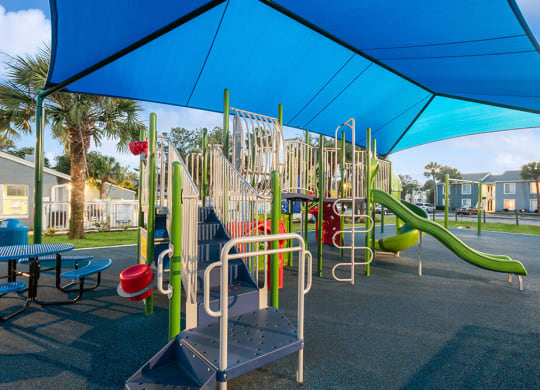 Community Playground with a Slide and Blue Canopy at Park at 7200 Apartments in Jacksonville, FL.