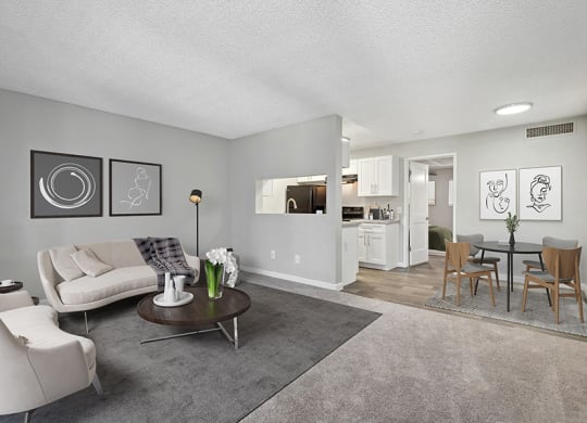 Model Living Room with Carpet and View of Kitchen/Dining Area at Stillwater Apartments in Glendale, AZ.