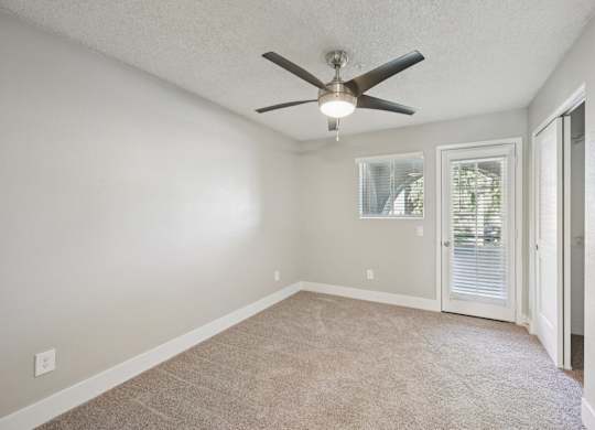 A room with a ceiling fan and carpeted floor.